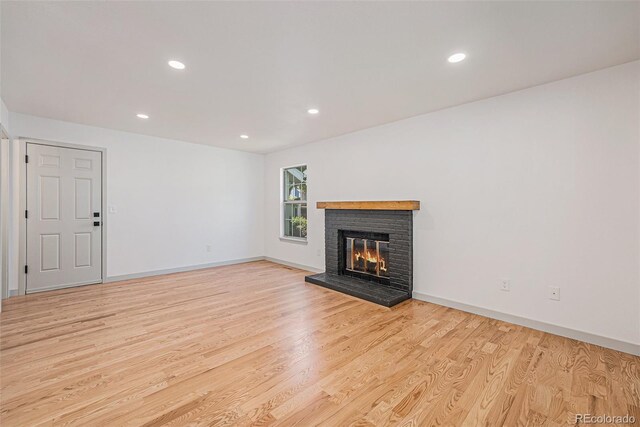9948 King St, Westminster, CO 80031 - unfurnished living room with light wood-type flooring, a brick fireplace, and recessed lighting