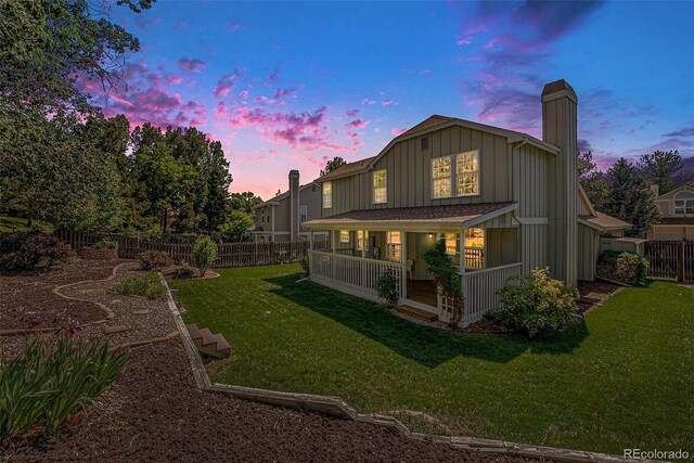 9948 King St, Westminster, CO 80031 - back of house featuring board and batten siding, a fenced backyard, a chimney, and covered porch