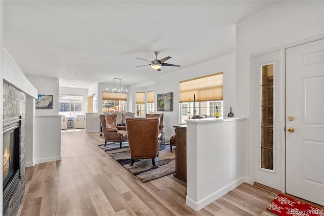 interior space with ceiling fan with notable chandelier and light wood-type flooring