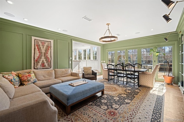 living area featuring ornamental molding, a healthy amount of sunlight, a decorative wall, and visible vents