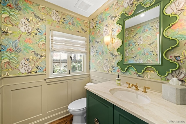 bathroom with a wainscoted wall, visible vents, a decorative wall, toilet, and vanity