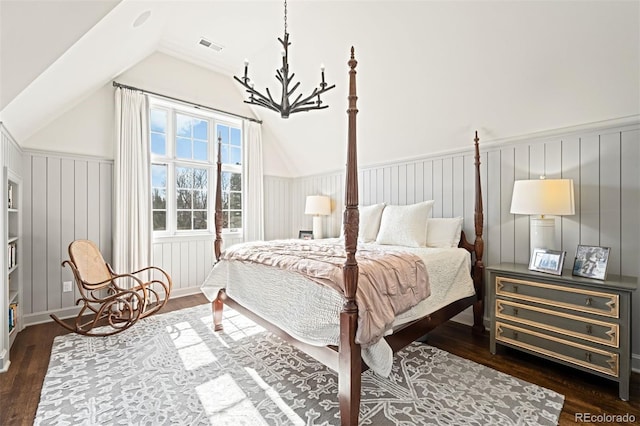 bedroom with lofted ceiling, visible vents, wainscoting, dark wood-style floors, and an inviting chandelier