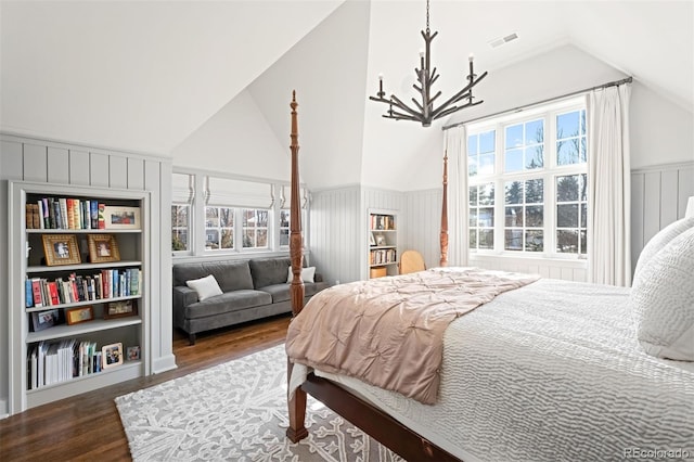 bedroom featuring a notable chandelier, wood finished floors, visible vents, vaulted ceiling, and wainscoting