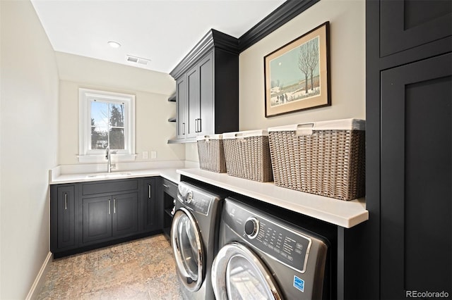 clothes washing area featuring a sink, visible vents, baseboards, cabinet space, and washer and clothes dryer