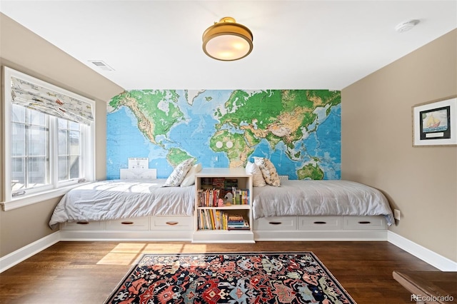 bedroom with baseboards, an accent wall, visible vents, and dark wood-style flooring