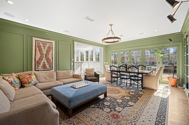 living room with visible vents, a decorative wall, ornamental molding, and recessed lighting