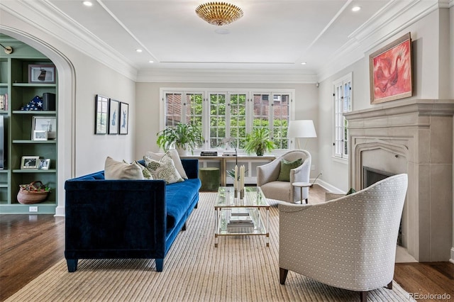 sitting room featuring wood finished floors, a fireplace, arched walkways, ornamental molding, and recessed lighting
