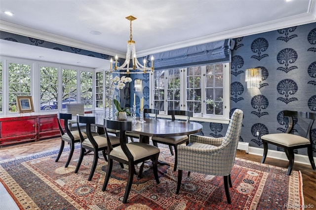 dining space featuring baseboards, ornamental molding, an inviting chandelier, and wood finished floors