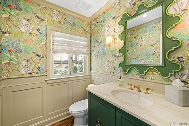 bathroom featuring wallpapered walls, visible vents, a decorative wall, vanity, and a wainscoted wall
