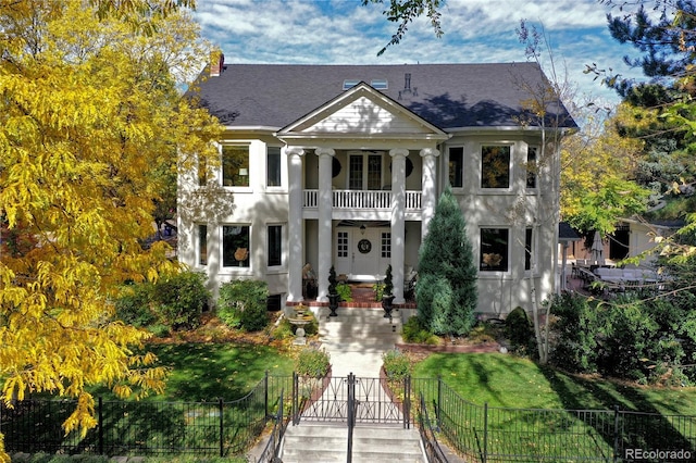 neoclassical / greek revival house featuring a front yard and a balcony