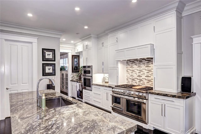 kitchen featuring dark stone countertops, white cabinets, stainless steel appliances, and sink