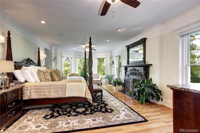 bedroom with ceiling fan, multiple windows, and light wood-type flooring