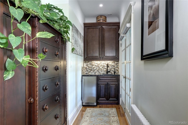 bar with backsplash, radiator heating unit, hardwood / wood-style floors, and stainless steel fridge