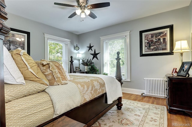 bedroom with radiator, ceiling fan, multiple windows, and hardwood / wood-style floors