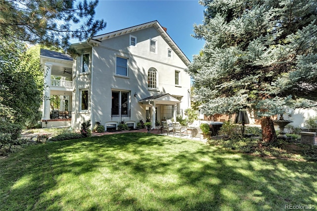 view of front facade featuring a patio area, a front lawn, ceiling fan, and a balcony