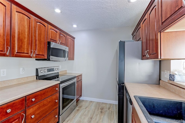 kitchen featuring stainless steel appliances, light hardwood / wood-style floors, sink, and a textured ceiling