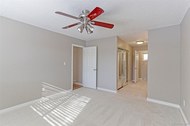 spare room with ceiling fan, light colored carpet, and a textured ceiling