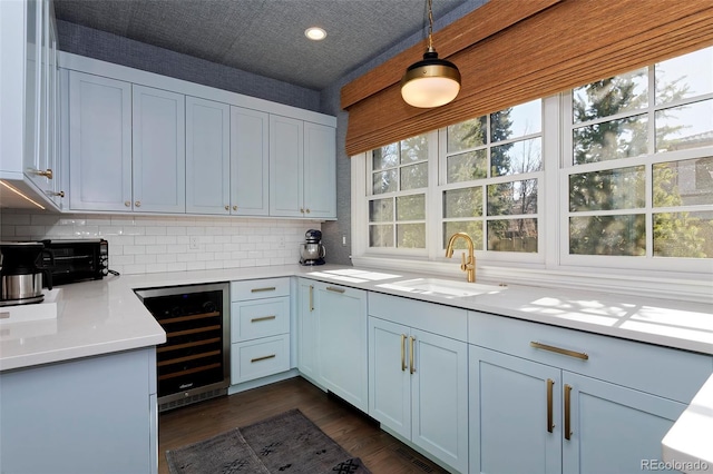 kitchen with beverage cooler, decorative light fixtures, sink, and backsplash