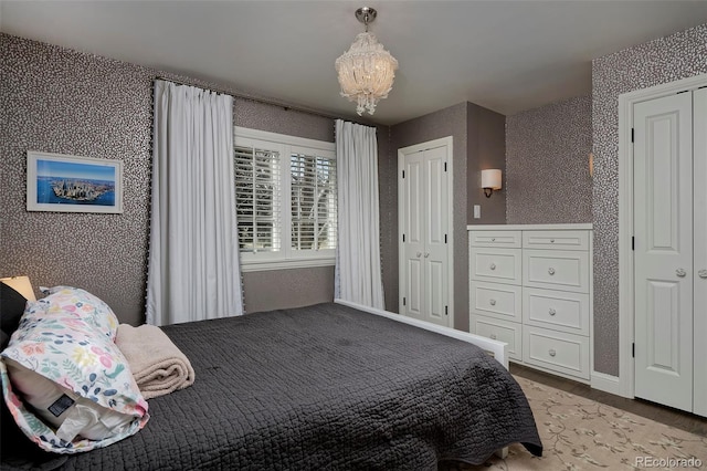 bedroom with two closets, a chandelier, and light wood-type flooring