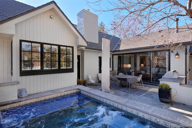 back of house featuring a jacuzzi, a patio area, and an outdoor kitchen