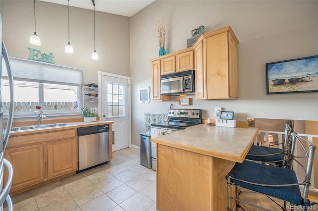 8893 W Ontario Ave, Littleton, CO 80128 - kitchen featuring light brown cabinets, a peninsula, decorative light fixtures, appliances with stainless steel finishes, and a sink
