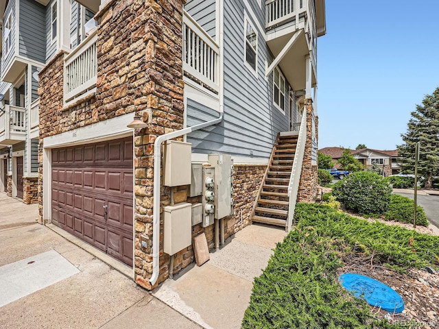 9363 Amison Cir Unit 106, Parker, CO 80134 - view of property exterior featuring stone siding, an attached garage, stairway, and driveway
