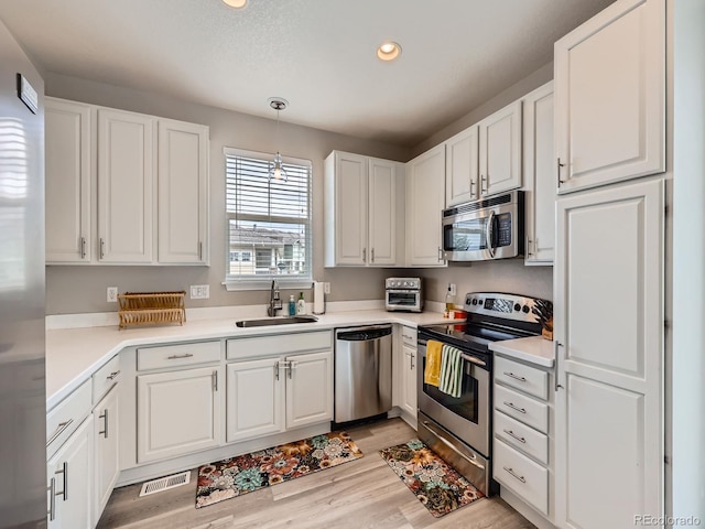 9363 Amison Cir Unit 106, Parker, CO 80134 - kitchen featuring stainless steel appliances, a sink, white cabinetry, light wood-style flooring, and recessed lighting