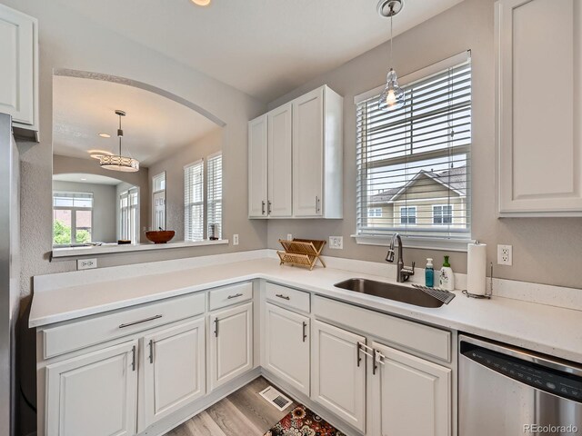 9363 Amison Cir Unit 106, Parker, CO 80134 - kitchen with stainless steel dishwasher, a sink, arched walkways, white cabinetry, and hanging light fixtures