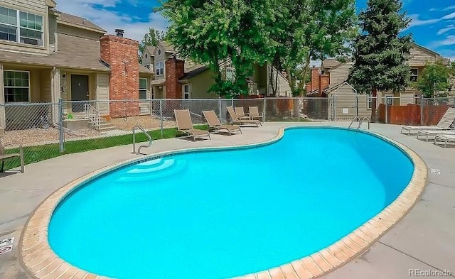 community pool with fence, a patio area, and a residential view