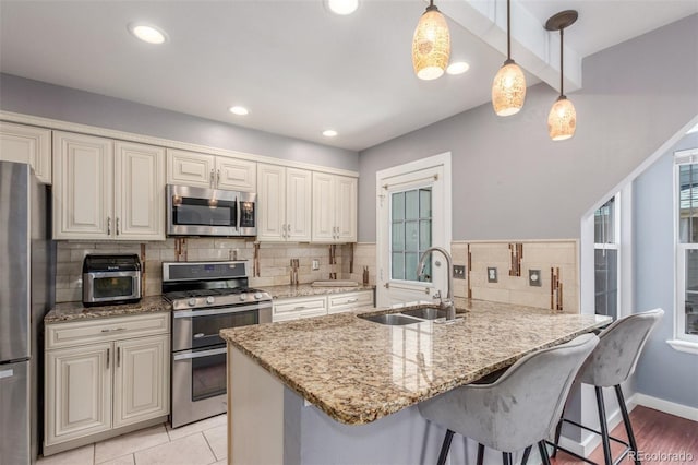 kitchen featuring a sink, appliances with stainless steel finishes, backsplash, and a peninsula