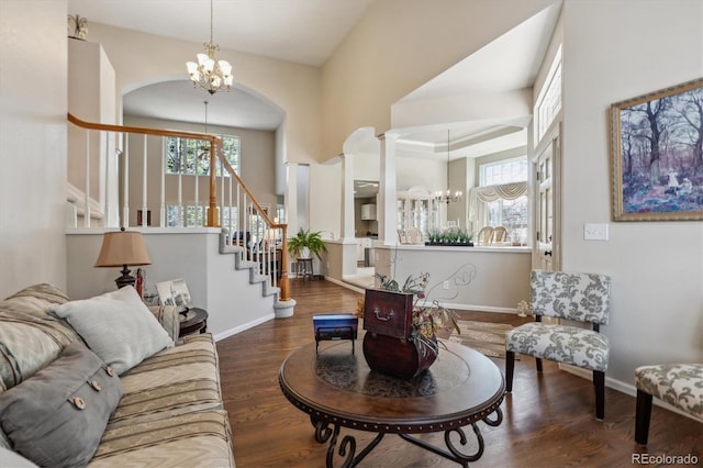 living area featuring a notable chandelier, stairs, baseboards, and wood finished floors