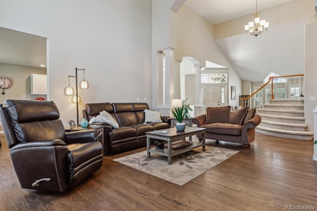 living area with stairway, high vaulted ceiling, wood finished floors, and decorative columns