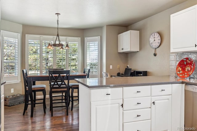 kitchen featuring backsplash, dishwasher, a peninsula, white cabinets, and dark wood-style flooring