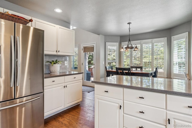 kitchen featuring wood finished floors, white cabinetry, freestanding refrigerator, dark stone counters, and decorative backsplash