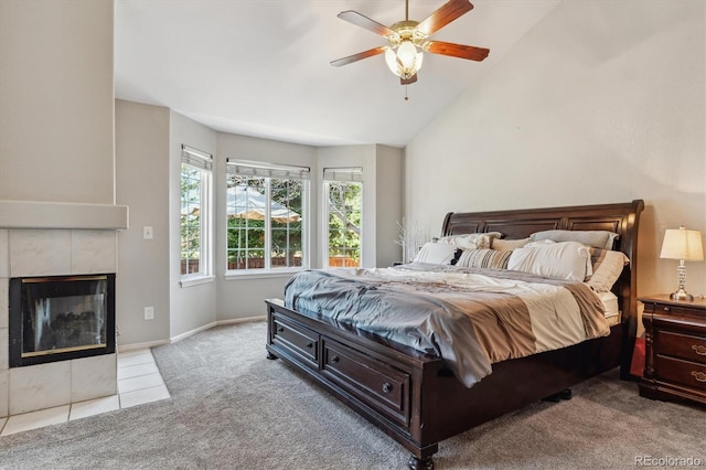 bedroom featuring lofted ceiling, a ceiling fan, a tiled fireplace, carpet floors, and baseboards