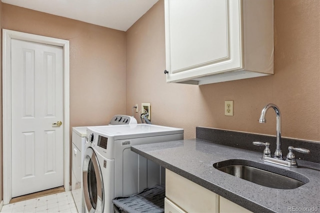 clothes washing area with a sink, cabinet space, light floors, and independent washer and dryer