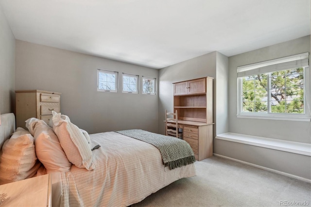 bedroom with multiple windows, light carpet, and baseboards