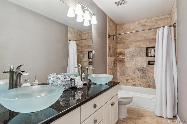 bathroom with a sink, visible vents, toilet, and double vanity