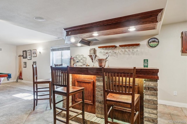 bar with baseboards, a bar, and light tile patterned flooring