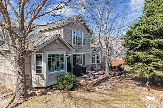 rear view of house with brick siding and a shingled roof