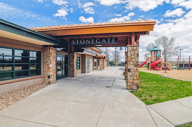 exterior space with concrete driveway and stone siding