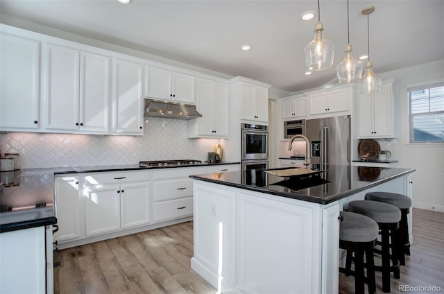 kitchen featuring a center island with sink, stainless steel appliances, and white cabinets