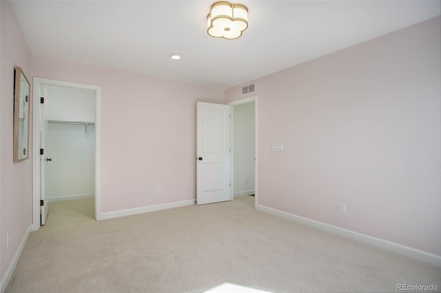 unfurnished bedroom with light carpet, a closet, and a walk in closet