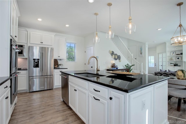 kitchen with appliances with stainless steel finishes, hanging light fixtures, sink, and an island with sink