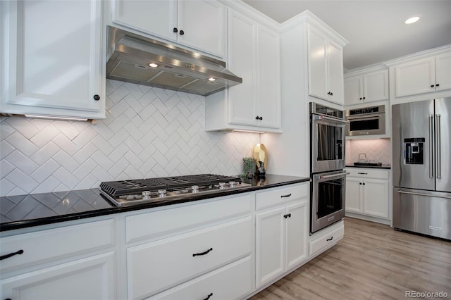 kitchen with light wood-type flooring, white cabinets, stainless steel appliances, and tasteful backsplash