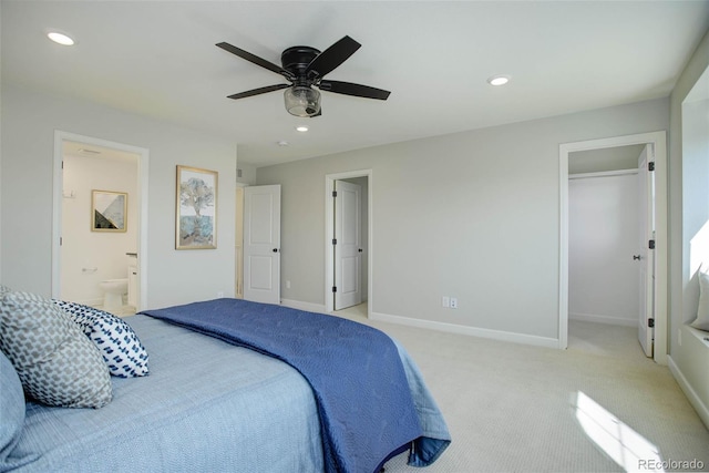 bedroom with ceiling fan, light colored carpet, a closet, and ensuite bath