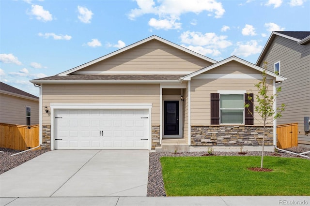 view of front of house with fence, a front yard, stone siding, concrete driveway, and an attached garage
