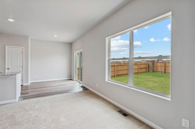unfurnished living room featuring baseboards, carpet, a healthy amount of sunlight, and visible vents