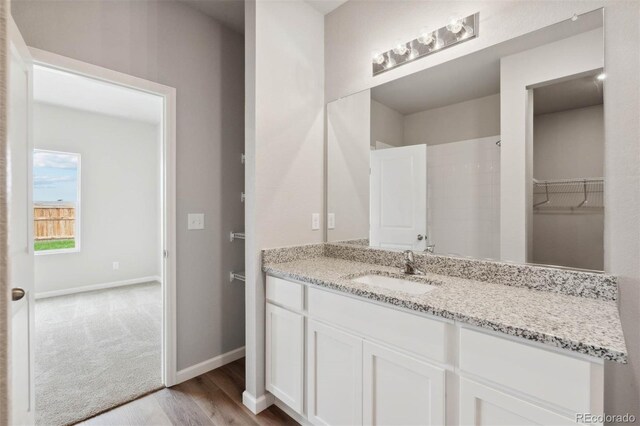full bath with baseboards, wood finished floors, and vanity