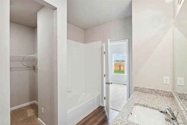 full bathroom with shower / bathtub combination, baseboards, vanity, and a spacious closet